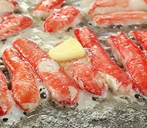 鉄板の上でバターと一緒に焼かれているカニのむき身
