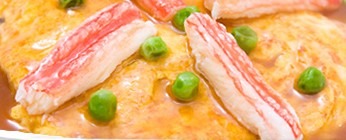 甘酢あんのかかったカニ玉にのったカニのむき身とグリーンピース