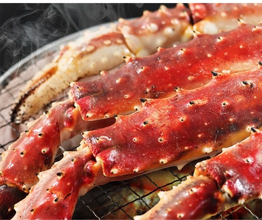 網の上で焼いている生のタラバの肩脚