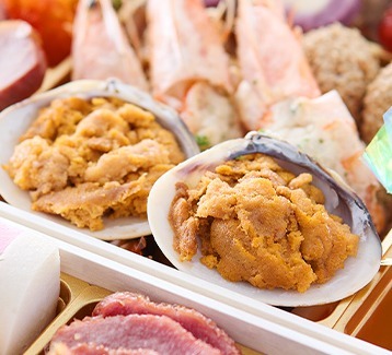貝殻に盛った焼き雲丹が2つ並び、奥に海老が見える