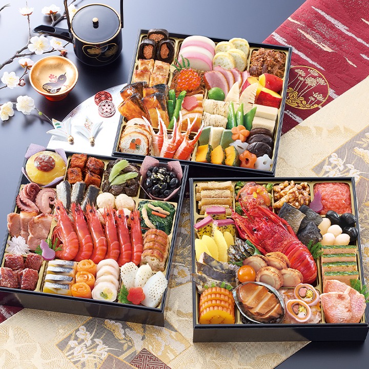 三段のお重を並べたおせち。ロブスター、赤い海老が6尾並ぶ段、黒豆や煮物の段が見える