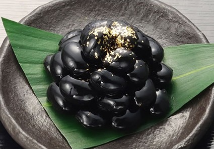 金箔をのせた黒豆を笹の葉の上に盛ったところ