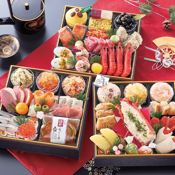 三段のお重を並べたおせち。赤い海老、生ハム、ロブスターのホワイトソース焼き、黒豆などが見える