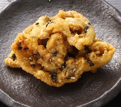 甘辛いたれをからめた揚げ鶏皮。白ごまがかかっている